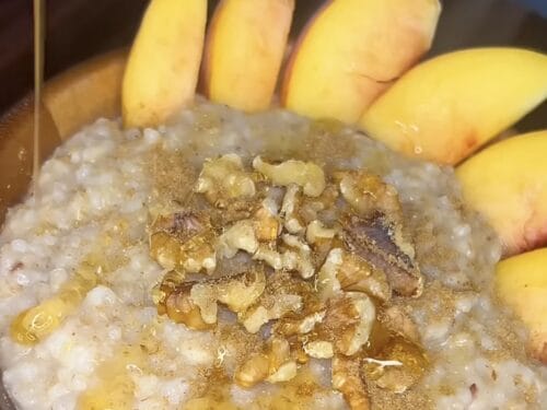 Pale porridge topped with chopped nuts and spices, surrounded by yellow squash halves
